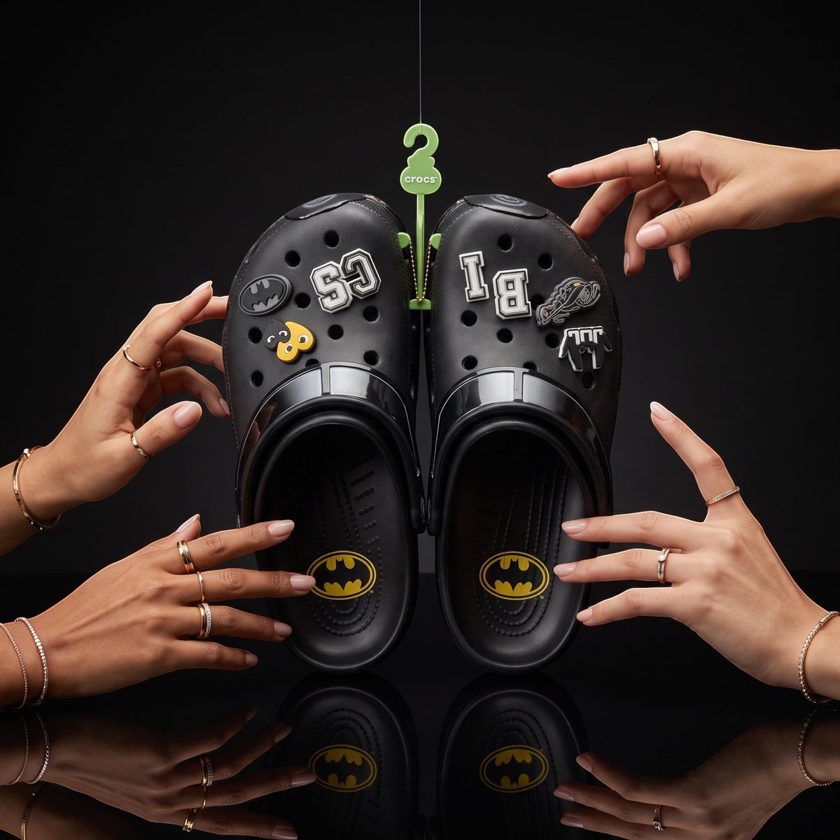 Paire de sabots noirs LAS ROSAS personnalisés avec des charms thématiques Benji sur fond noir avec mains féminines